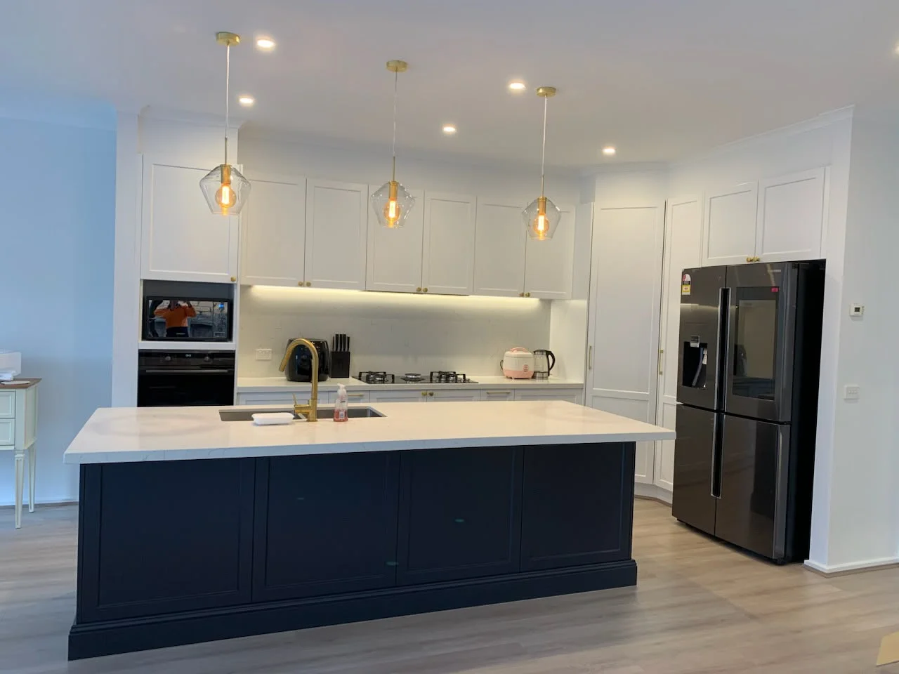 Kitchen with a dark island, white cabinetry and pendant lights