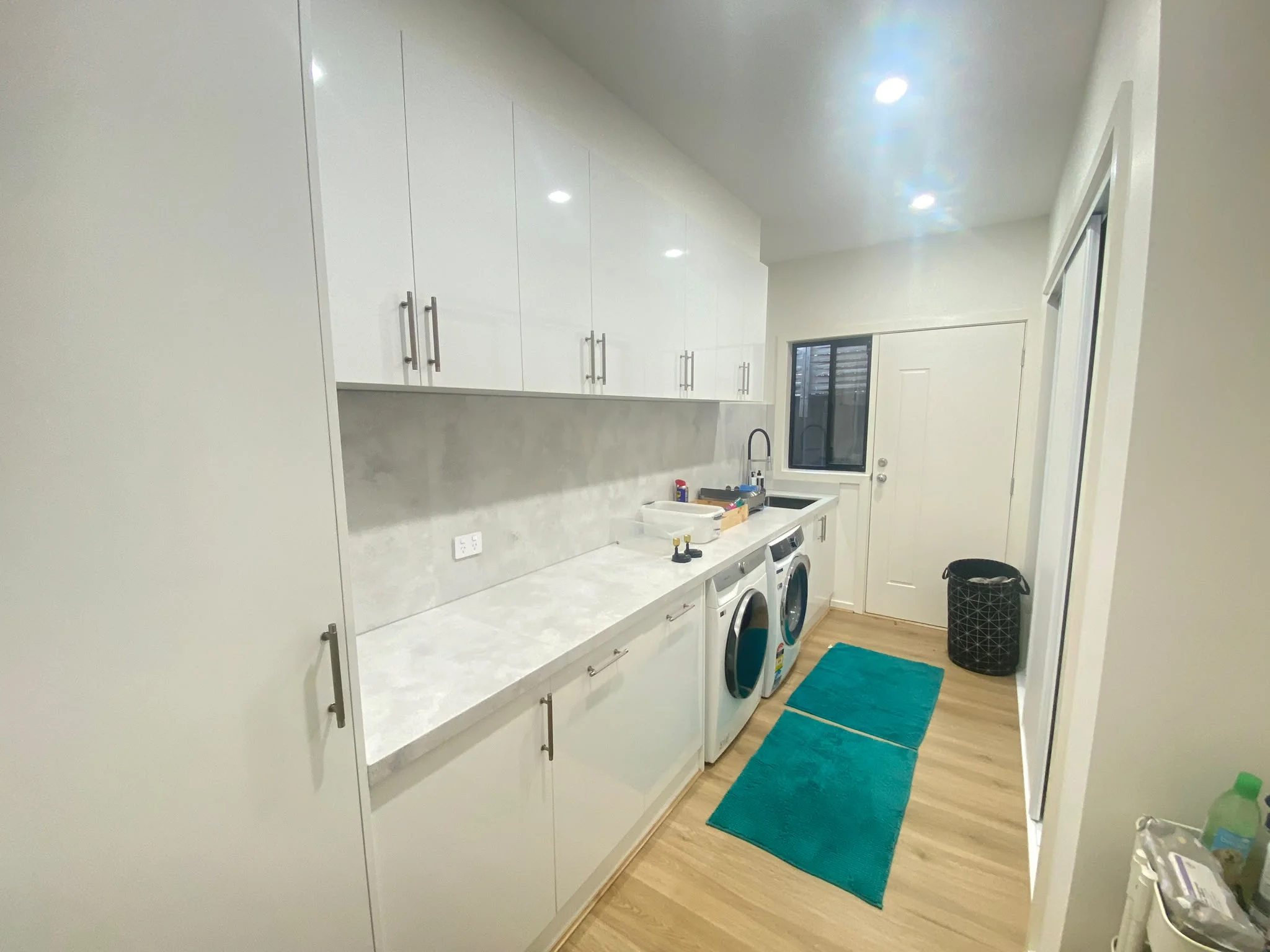 Laundry with fitted white cabinetry and a long benchtop